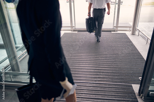 Airport male worker helping lady to carry luggage to the car