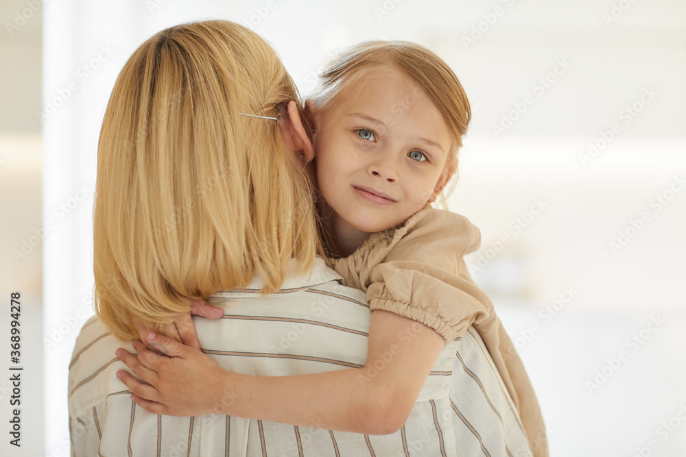 Warm-toned close up portrait of cute little girl embracing happy mother with love while sitting in her arms looking at camera and smiling, copy space Warm-toned close up portrait of cute little girl embracing happy mother with love while sitting in her arms looking at camera and smiling, copy space