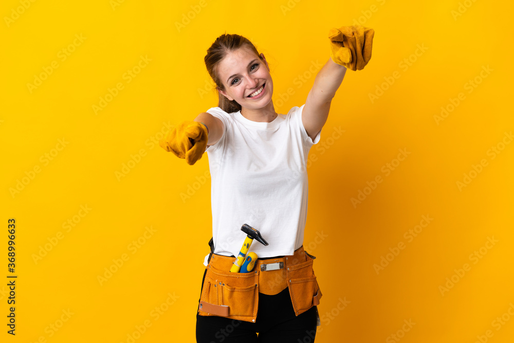 Young electrician woman isolated on yellow background points finger at you while smiling - obrazy, fototapety, plakaty 