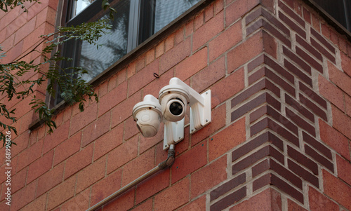 surveillance camera installed on the external brick wall of a residential building for security