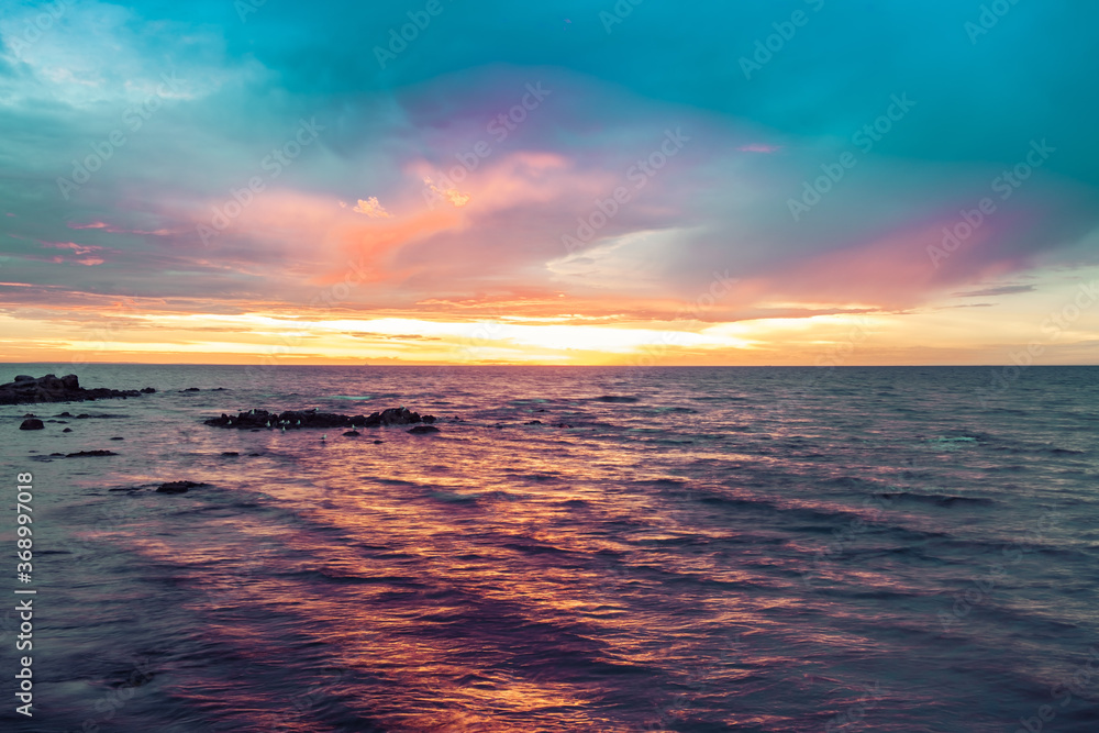 Colorful sunset over water with seagulls on rocks