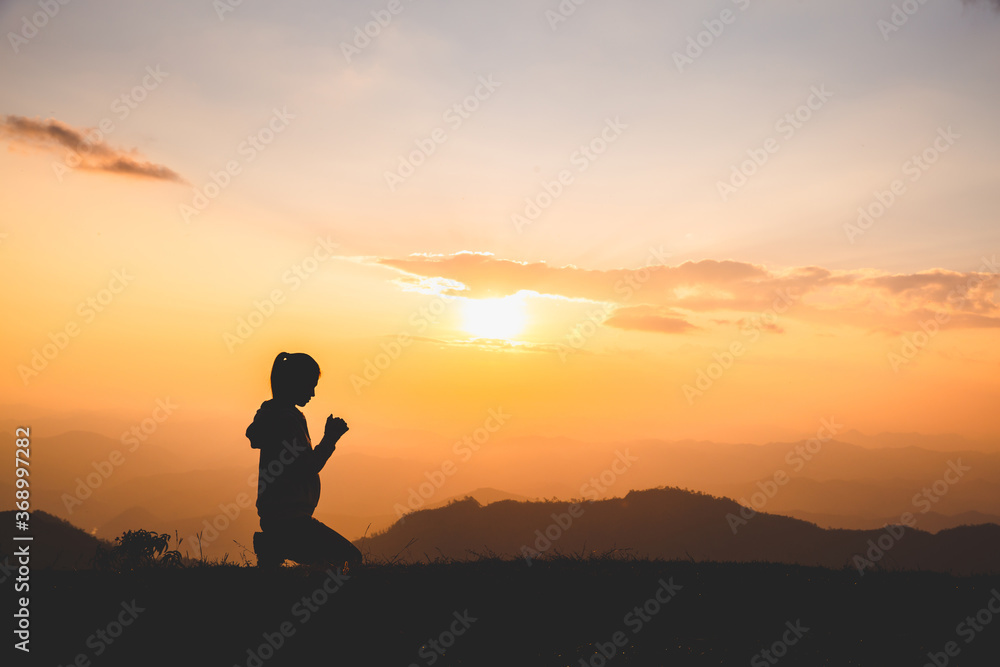 Silhouette of Christian woman praying worship at sunset. Christian