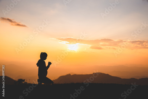 Fotografia Silhouette of Christian woman praying worship at sunset
