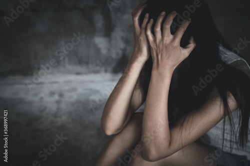 Young women sitting in dark room feeling pain with life problem. suffering from husband violence, Stop violence against and sexual abuse women, domestic violence, human trafficking.
