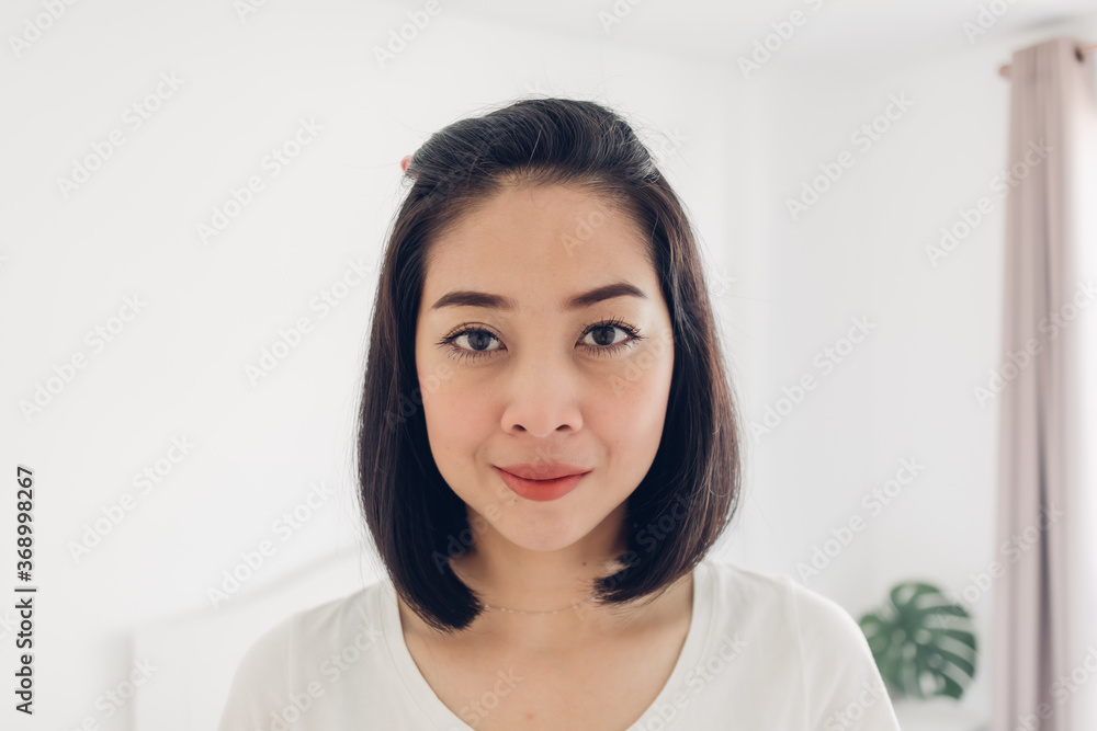 Straight portrait of Asian woman standing in white bedroom. Straight portrait of Asian woman standing in white bedroom.