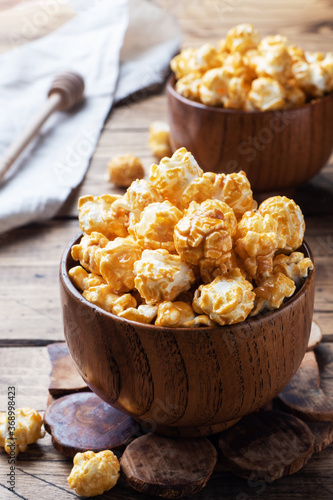 Popcorn in caramel glaze in wooden plates on a rustic table.