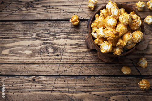 Popcorn in caramel glaze in wooden plates on a rustic table. Copy space. photo