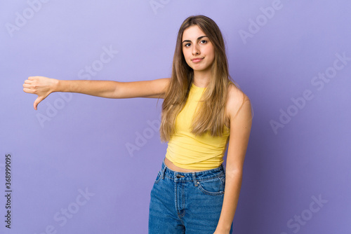 Young woman over isolated purple background showing thumb down with negative expression © luismolinero