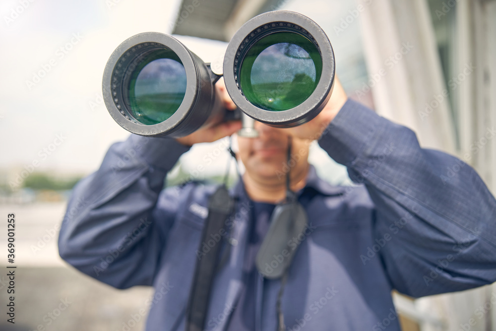 Handsome adult man looking away through binoculars Handsome adult man looking away through binoculars