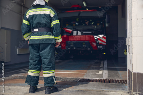 Tall man wearing protective green uniform standing at the fire station