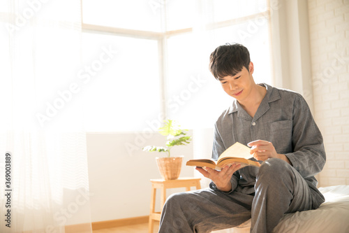 man in pajamas reading a book on bed