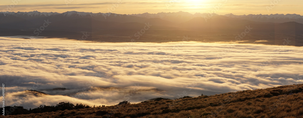 Naklejka premium Sunrise with orange cloud cover seen from Luxmore Hut in the Fiordland National Park along the Kepler Track near Te Anau in New Zealand.