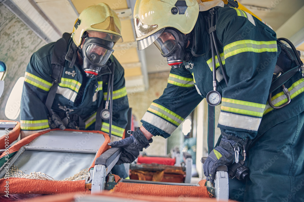 Firemen in protective masks and safe helmets investigating an emergency place Firemen in protective masks and safe helmets investigating an emergency place