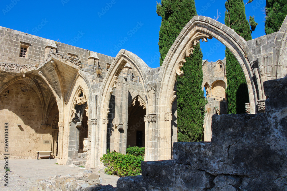 Arches of Bellapais Abbey, White Abbey, Abbey of the Beautiful world. Cypress trees against a blue sky.