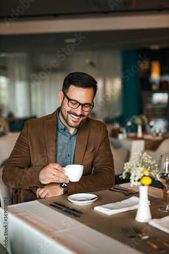 Happy man with a cup of coffee in the morning, at hotel dinning room, portrait.