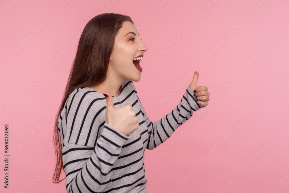Excellent job, I like it! Side view of joyful excited woman in striped sweatshirt doing thumbs up and shouting in happiness, satisfied with awesome result, successful project. studio shot isolated Excellent job, I like it! Side view of joyful excited woman in striped sweatshirt doing thumbs up and shouting in happiness, satisfied with awesome result, successful project. studio shot isolated