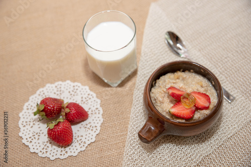 oatmeal porridge with strawberries and a glass of milk