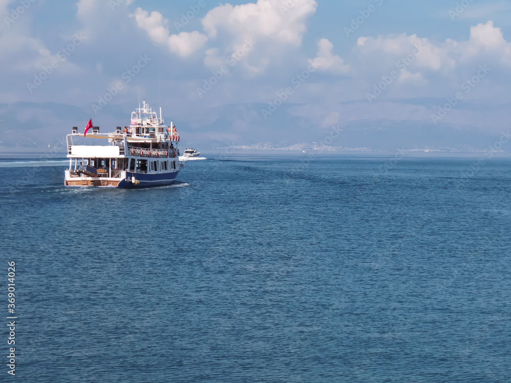 Turkish two open deck pleasure boat sailing in a calm Aegean sea in a bright day with some clouds with a Greek island on the background Turkish two open deck pleasure boat sailing in a calm Aegean sea in a bright day with some clouds with a Greek island on the background