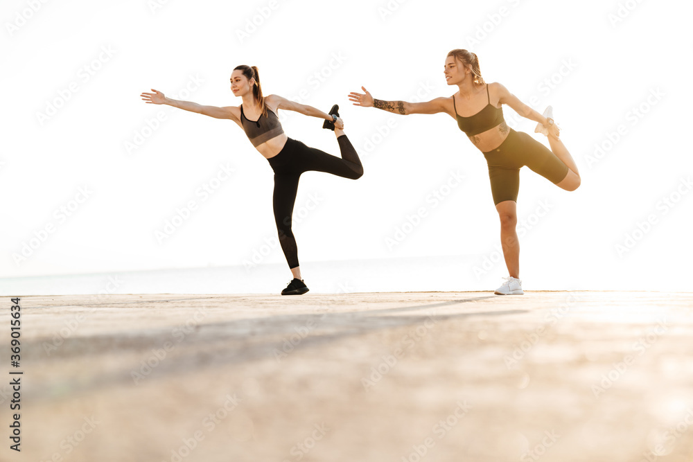 Women friends outdoors making stretching exercises Women friends outdoors making stretching exercises