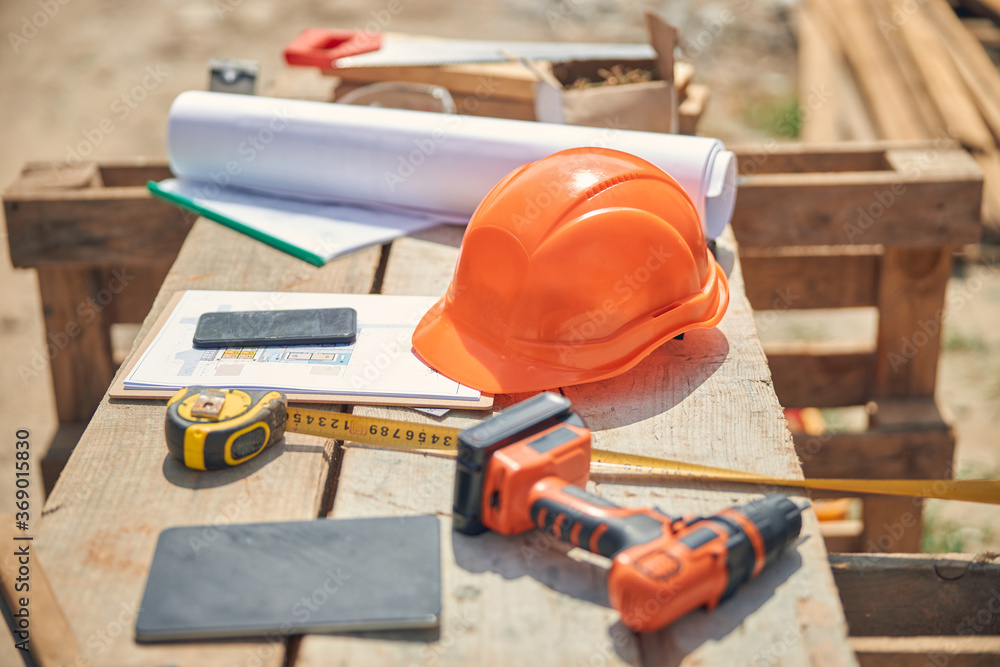 Orange protective helmet and builder instruments outside