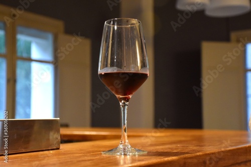 Glass cup with aged red wine on a wooden bar counter.