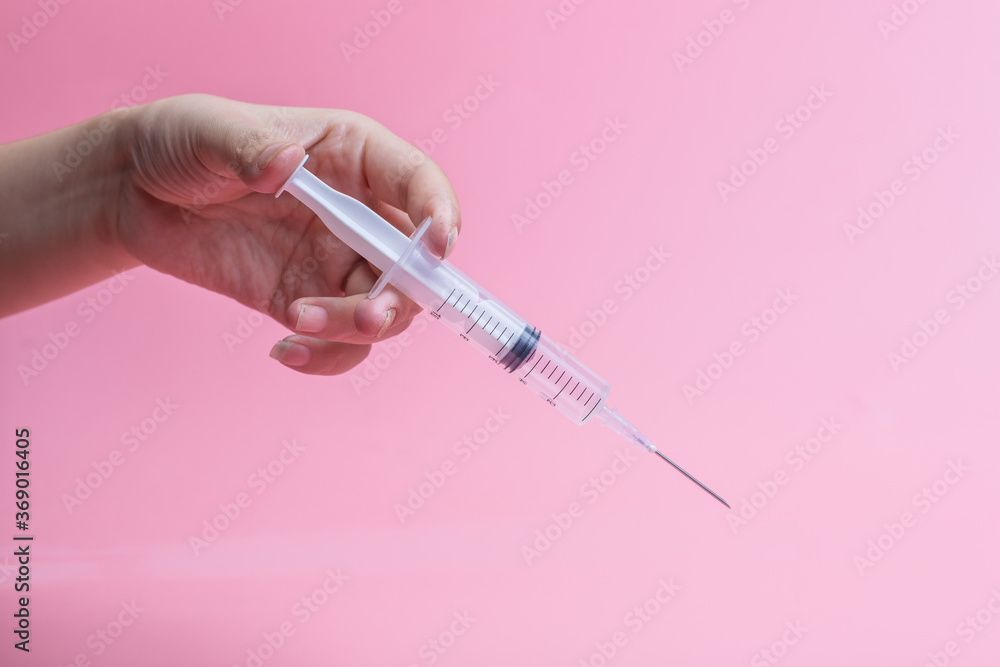 Hand holding syringe on pink background
Hand holding syringe on pink background