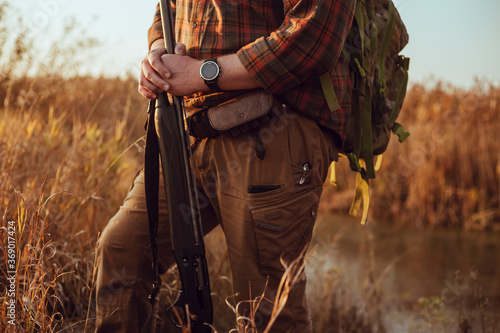 Masculine hunters hands, holding shotgun, in the sunset light, waiting for the duck