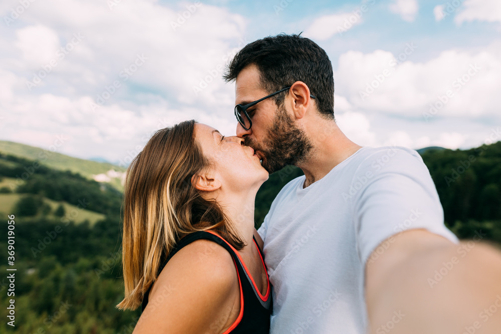 Young couple taking a selfie while kissing in the mountains Young couple taking a selfie while kissing in the mountains