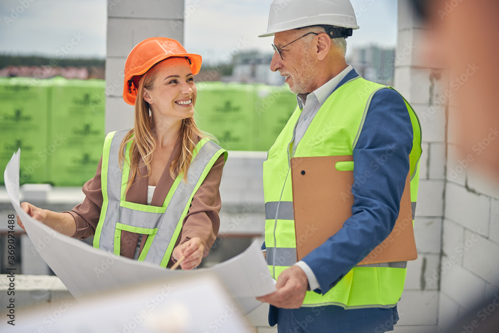 Cheerful lady in a helmet communicating with a foreman Cheerful lady in a helmet communicating with a foreman