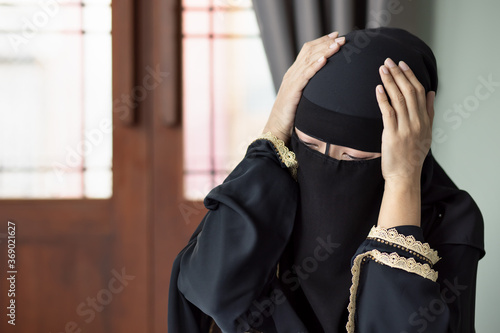 sick Middle Eastern muslim woman having fever and headache due to virus infection; concept of biohazard, biological hazard, health care, coronavirus disease outbreak, COVID-19 coronavirus
