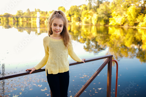 Autumn, a girl stands on the pier and smiles, a beautiful blonde enjoys a walk near the river