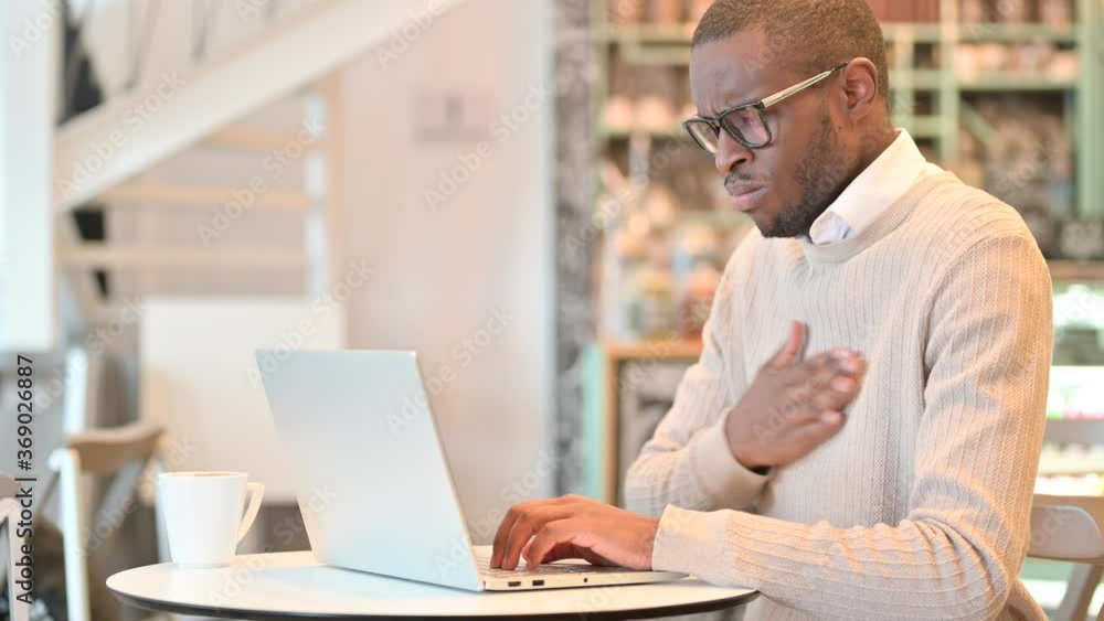 Sick African Man with Laptop Coughing in Cafe Sick African Man with Laptop Coughing in Cafe