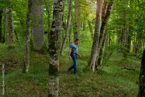 Adult man enjoys walking through the green forest in summer