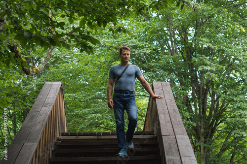 Man hiking through the forest, crossing a wooden bridge