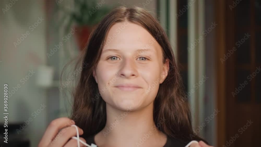 Portrait girl with medical face mask looking at camera removes the mask at home coronavirus covid-19 outbreak indoor safety pandemic slow motion Portrait girl with medical face mask looking at camera removes the mask at home coronavirus covid-19 outbreak indoor safety pandemic slow motion