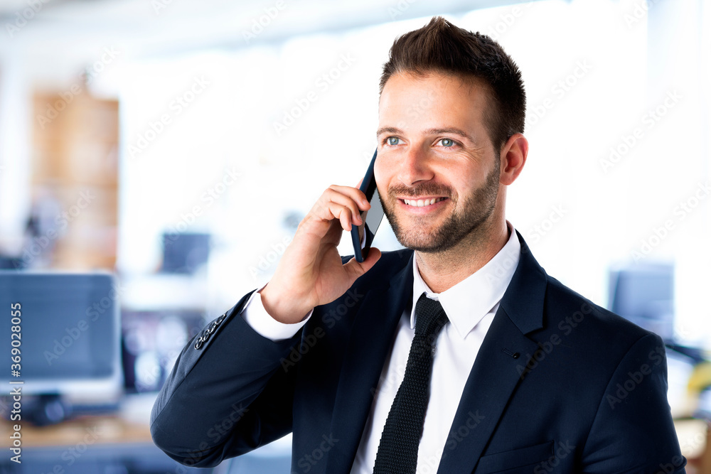 Portrait shot of businessman wearing suit and making a business call while standing in the office. Portrait shot of businessman wearing suit and making a business call while standing in the office.