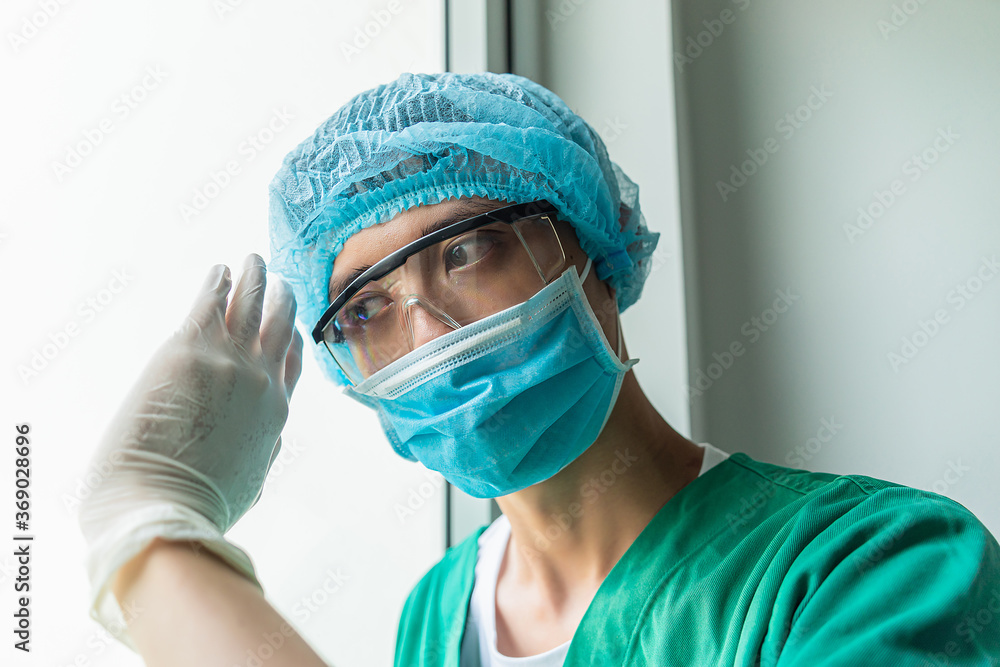 Tired doctor at the hospital looking through a window. The fight against the disease, viruses. Close up shot. Surgeon after surgery. Selected focus Tired doctor at the hospital looking through a window. The fight against the disease, viruses. Close up shot. Surgeon after surgery. Selected focus