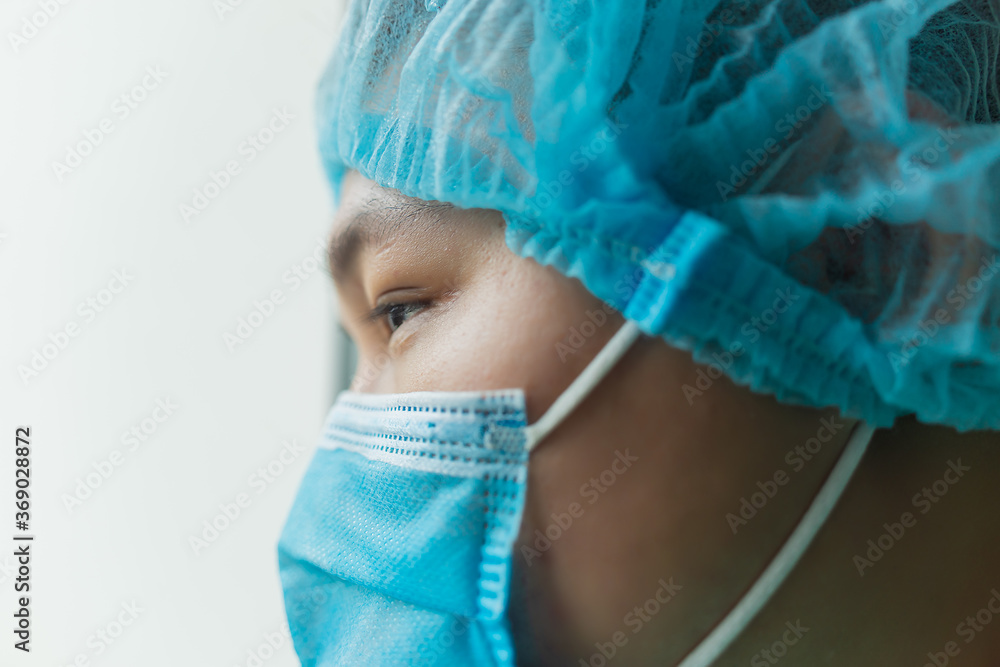 Tired doctor at the hospital looking through a window. The fight against the disease, viruses. Close up shot. Surgeon after surgery. Selected focus Tired doctor at the hospital looking through a window. The fight against the disease, viruses. Close up shot. Surgeon after surgery. Selected focus