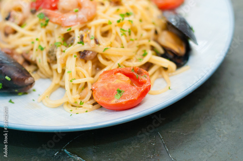 Spaghetti pasta with shrimp, mussels, tomatoes and cheese, close-up, copy space. Tasty, traditional food from Italy