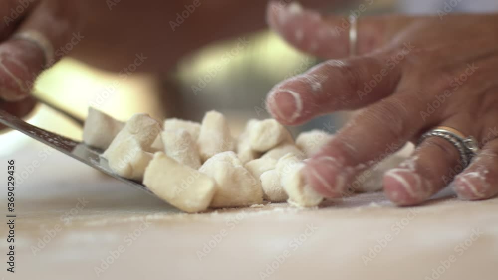 Woman making homemade pasta potato gnocchi. Dropping the dough pieces onto the floured wooden table. Woman making homemade pasta potato gnocchi. Dropping the dough pieces onto the floured wooden table.