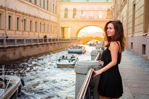 A pretty girl walks through the summer of St. Petersburg and stopped on the embankment, along the channels of which excursion boats go. Russian tourism © KseniaJoyg