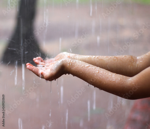 Kids hand in drizzling rain water. Kids playing in rain water