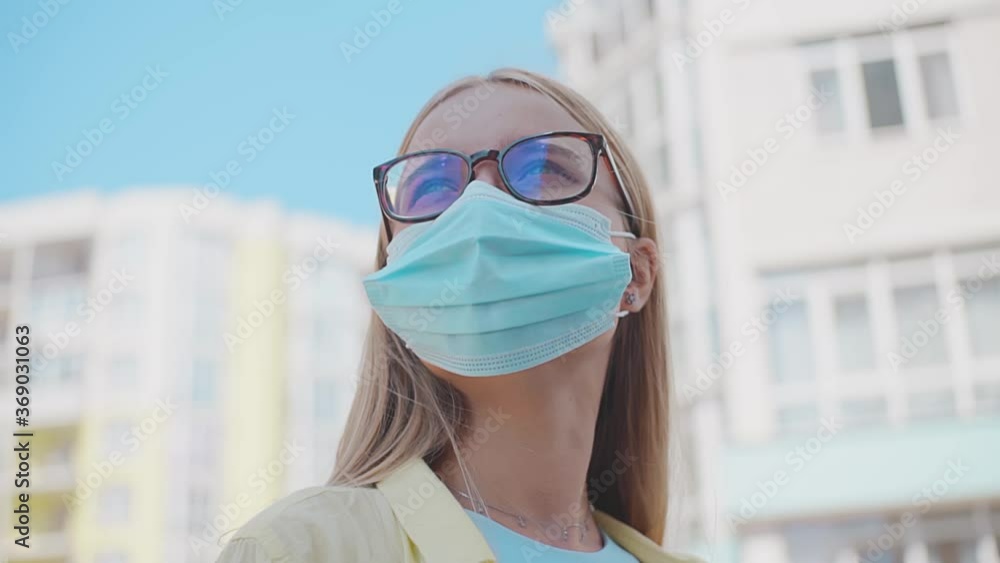 Portrait young woman with glasses looking around with medical mask being outdoors during quarantine pandemic covid-19 close up slow motion Portrait young woman with glasses looking around with medical mask being outdoors during quarantine pandemic covid-19 close up slow motion