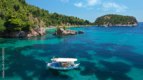 Aerial drone photo of beautiful fishing boat anchored in turquoise sea of Stafilos bay, Skopelos island, Sporades, Greece