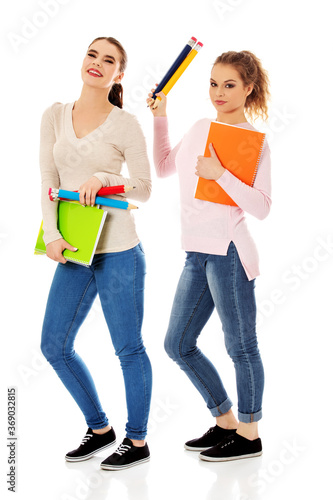 Portrait of a cute young student girls holding colorful notebooks, isolated on white background