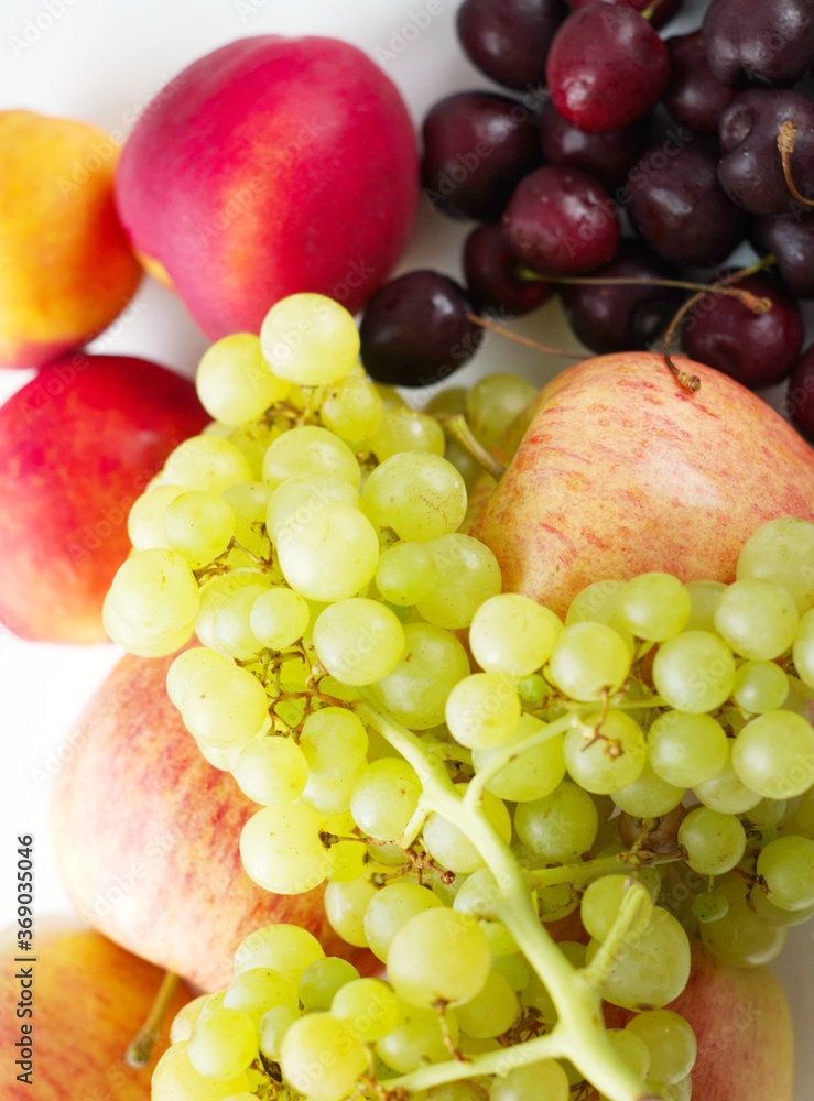 a set of fruits, a bunch of yellow quiche-mish grapes lies on ripe apples, next to cherries and peaches on a light surface. Natural fruit dessert. A tasty, healthy snack, a slice of summer, a harvest. a set of fruits, a bunch of yellow quiche-mish grapes lies on ripe apples, next to cherries and peaches on a light surface. Natural fruit dessert. A tasty, healthy snack, a slice of summer, a harvest.