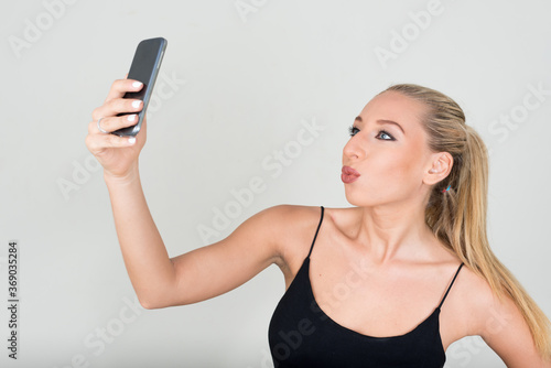 Portrait of young beautiful blonde woman taking selfie