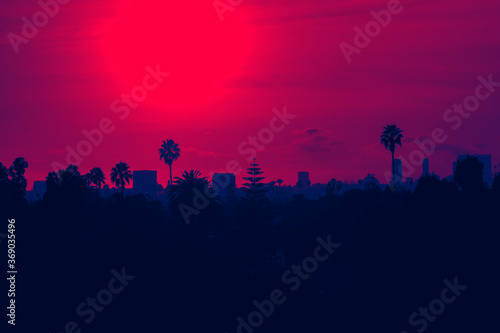 Sunset over Los Angeles skyline with buildings and palm trees in California - red and blue duotone colors