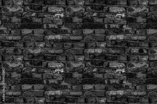 old shattered black stone wall part of the ruined house building in gloomy tones broken bricks