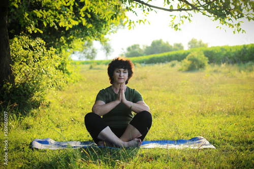 Beautiful mature woman doing yoga outdoors Active lifestyle Restart of normal life after the pandemic